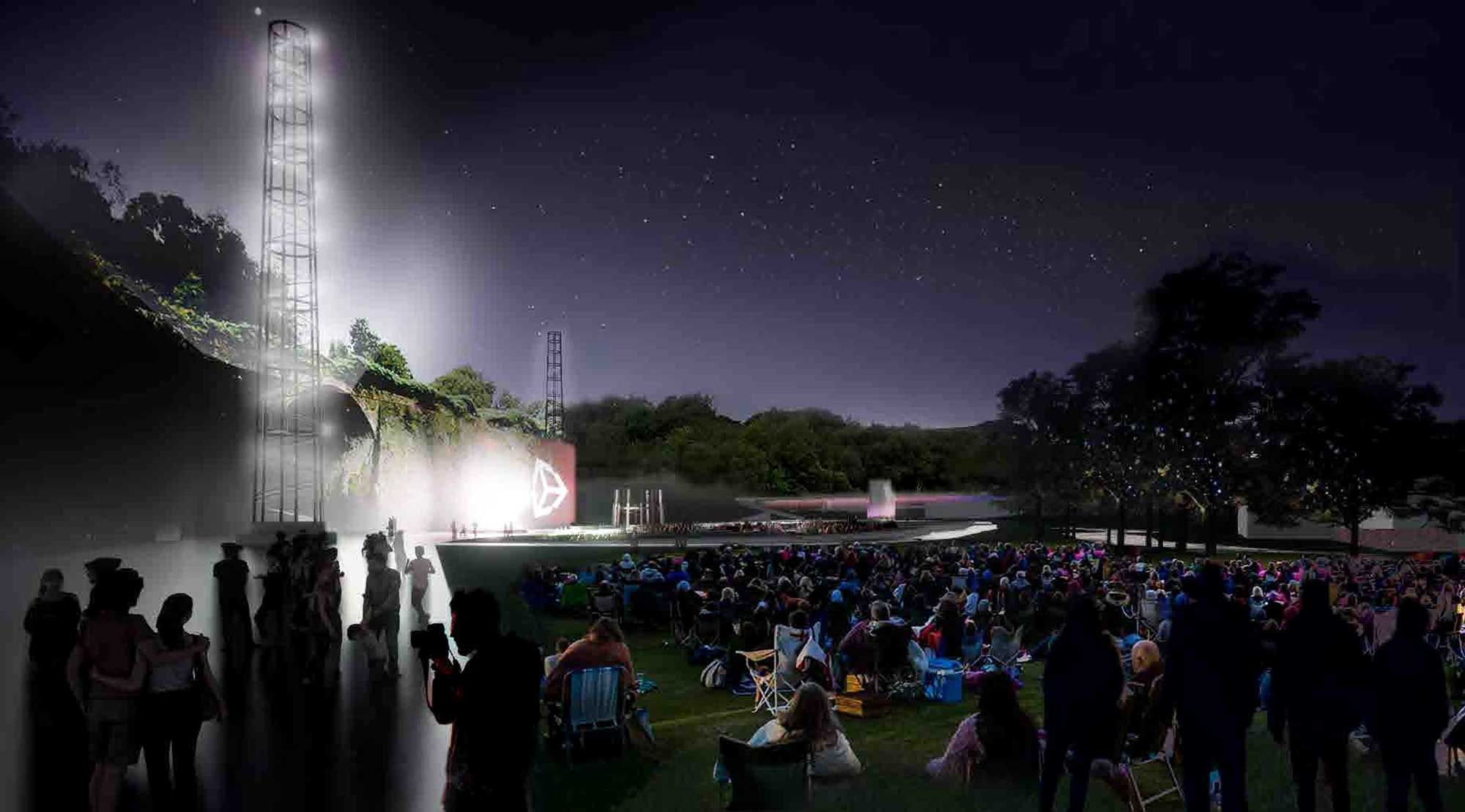 People sat in a field watching a bright stage at night.jpg People sat in a field watching a bright stage at night.jpg