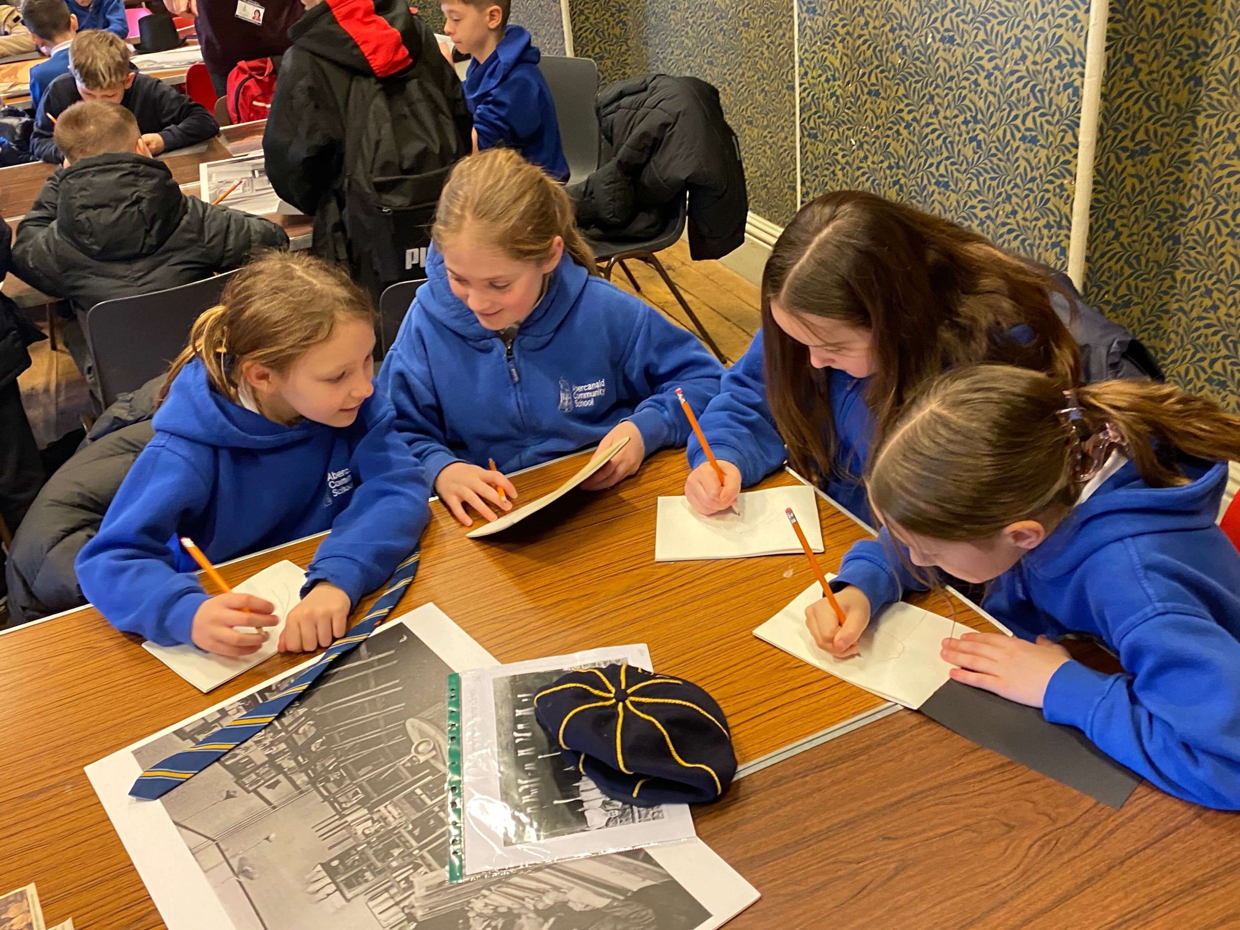 Children in blue uniform sitting around a table and writing..JPG